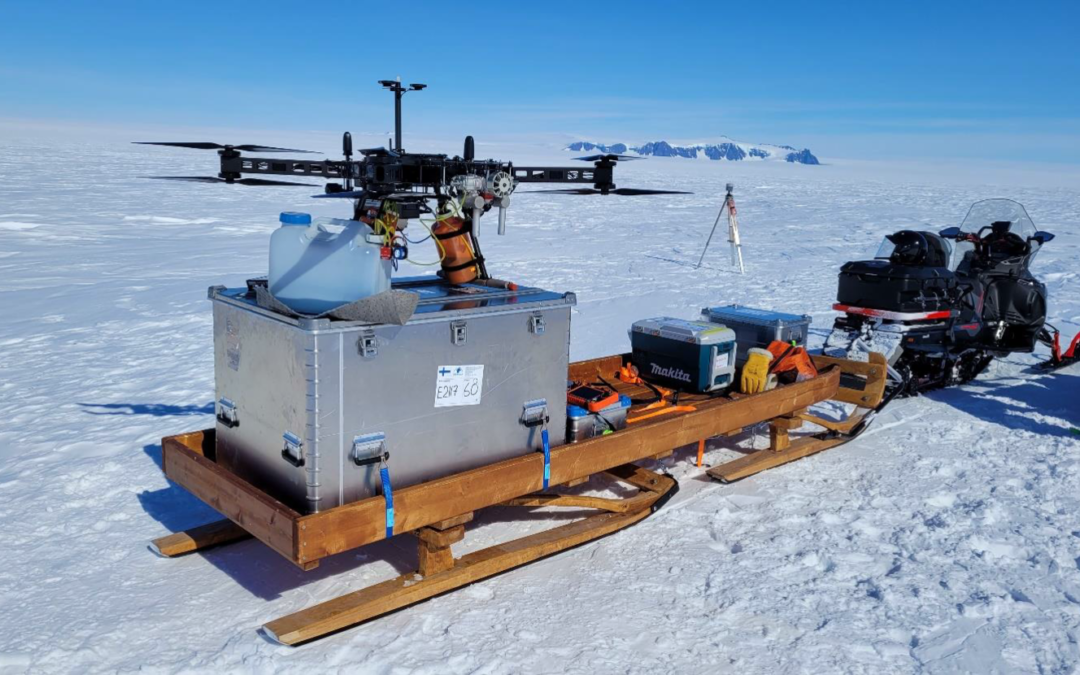 Snow mobile pulling a large research drone on ice field in Antarctica